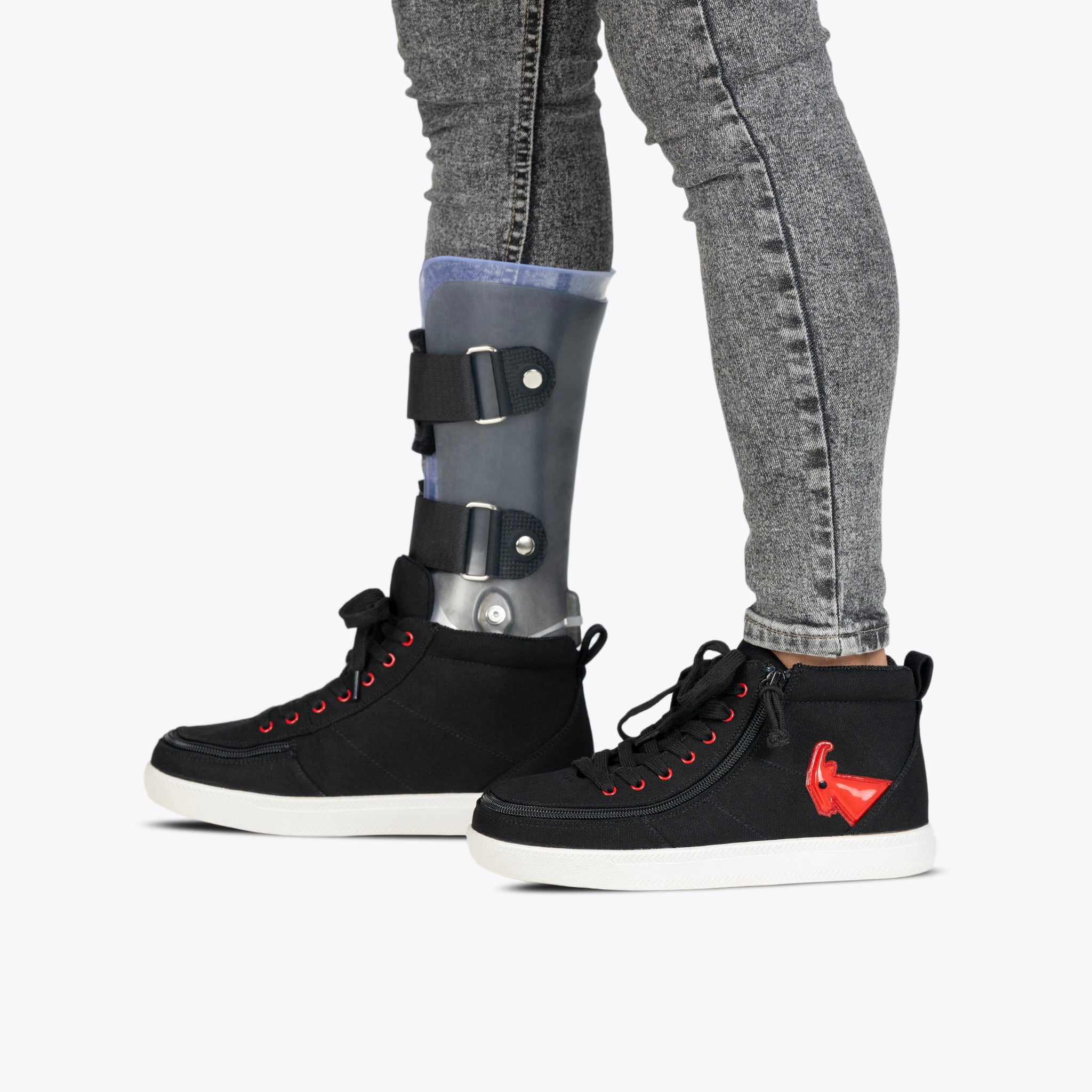 Person wearing gray jeans and an orthopedic brace partially inside Black/Red Light Ups BILLY Classic D|R High sneakers by BILLY Footwear; the shoes are AFO-friendly with removable insoles for comfort.