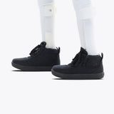 A person with white prosthetic legs wears Black to the Floor BILLY D|R II Short Wrap High sneakers by BILLY Footwear, featuring removable insoles, and white socks, standing on a light background.