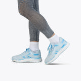 A person wearing gray textured leggings, white socks, and SALE - Sky Blue BILLY Sport Inclusion shoes by BILLY Footwear stands with one foot slightly raised on a plain white background.