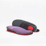 The Lilac Watercolor BILLY Limitless insoles by BILLY Footwear for kids’ orthopedic shoes feature a purple mesh top, red cushioning, and black textured soles. On a white background, one insole shows the top and the other displays the underside.