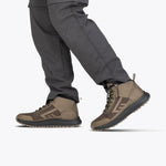 A person wearing gray cargo pants and taupe Men's BILLY Inclusion Trail Boots by BILLY Footwear, featuring an easy on/off zipper, stands against a plain white background.
