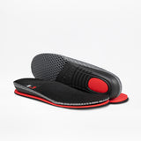 A pair of BILLY Footwear Men's Black Leather Comfort Luxe insoles—one flat, displaying the textured top in black, red, and gray; the other propped to show a dot-patterned sole with a red cushioned heel pad. Sensory-friendly for comfort.