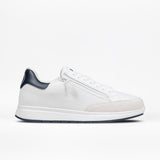 The Men's White/Navy BILLY Comfort Court by BILLY Footwear is a minimalist, low-cut white sneaker with a blue heel tab, white laces, and a white sole, shown in side profile on a white background.