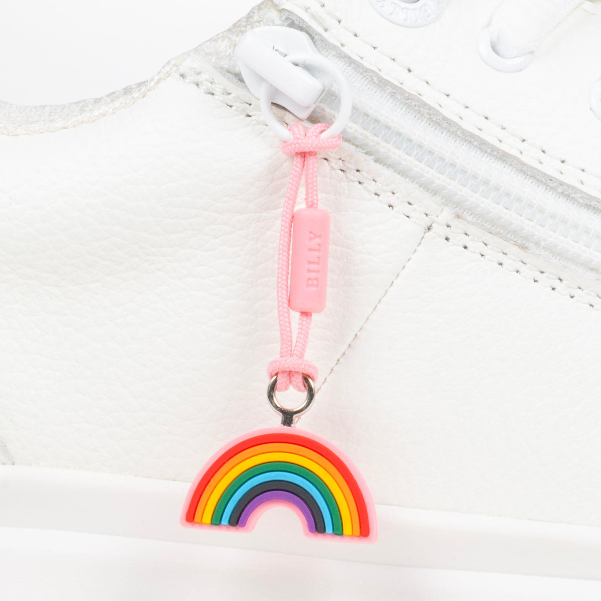 Rainbow charm on a white sneaker with a pink pull tab.