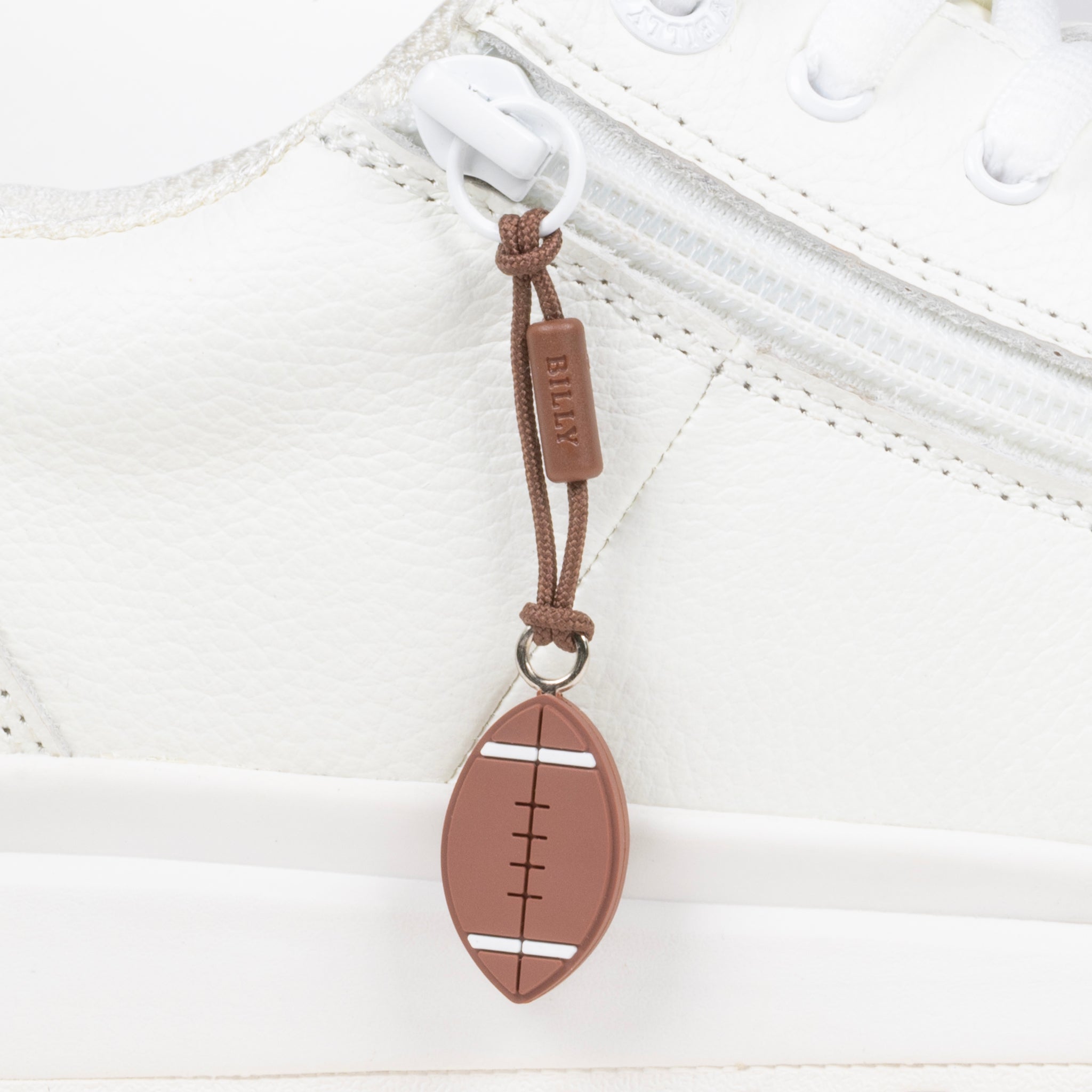 Brown football-shaped zipper pull attached to a white sneaker