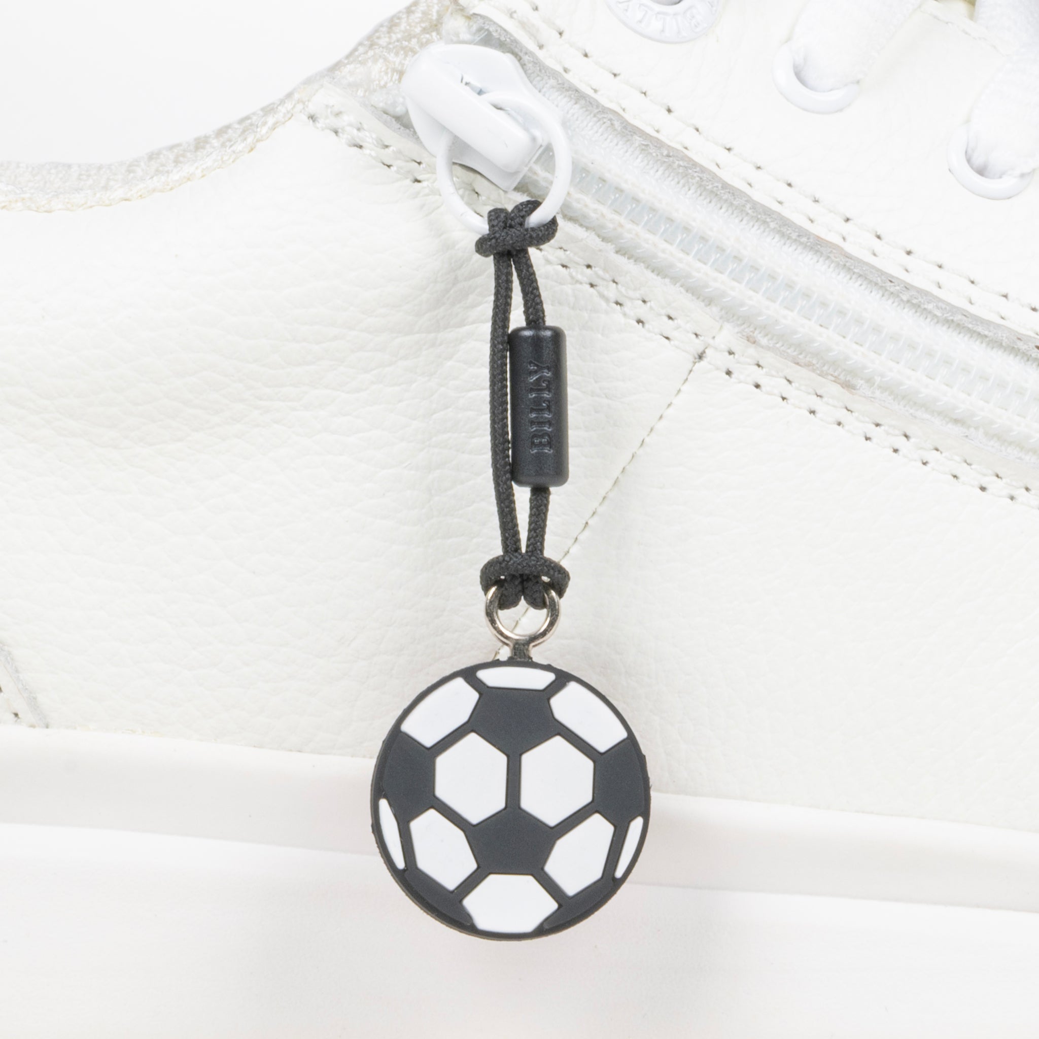 Black soccer ball zipper pull on a white shoe