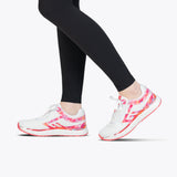 A person in black leggings and SALE - Women's Pink Marble BILLY Sport Inclusion sneakers by BILLY Footwear, featuring pink and red accents, stands on tiptoe against a plain white background.