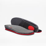 A pair of Women's Grey Suede BILLY Comfort Plush insoles by BILLY Footwear, featuring gray and black tones with red accents—one laid flat, the other angled to show off the textured underside and plush cushioning.