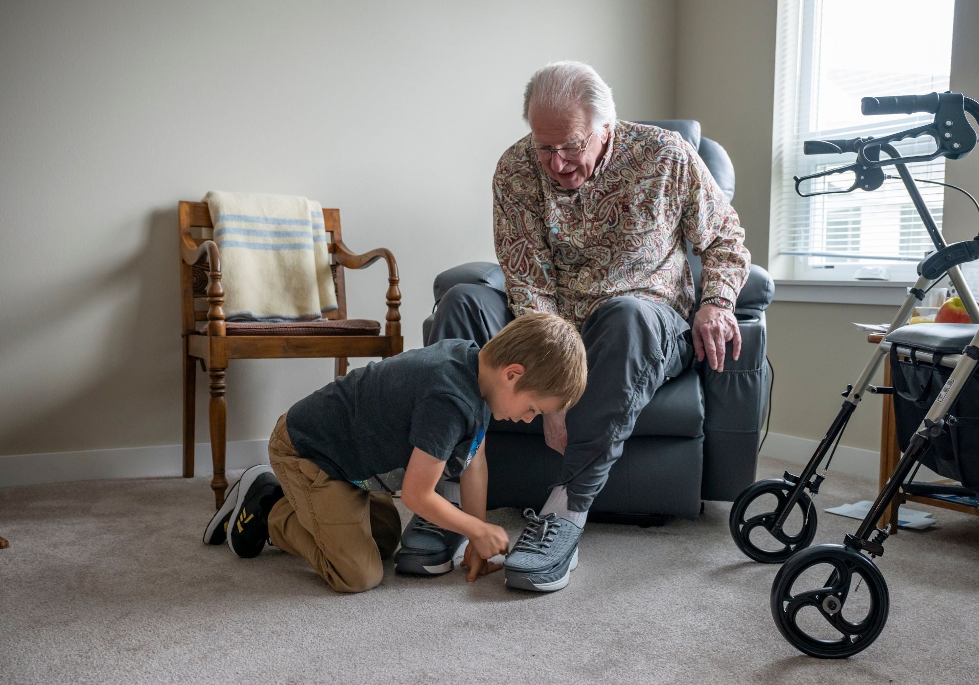Grandfather and grandson interacting in a home setting with a walker in the background.