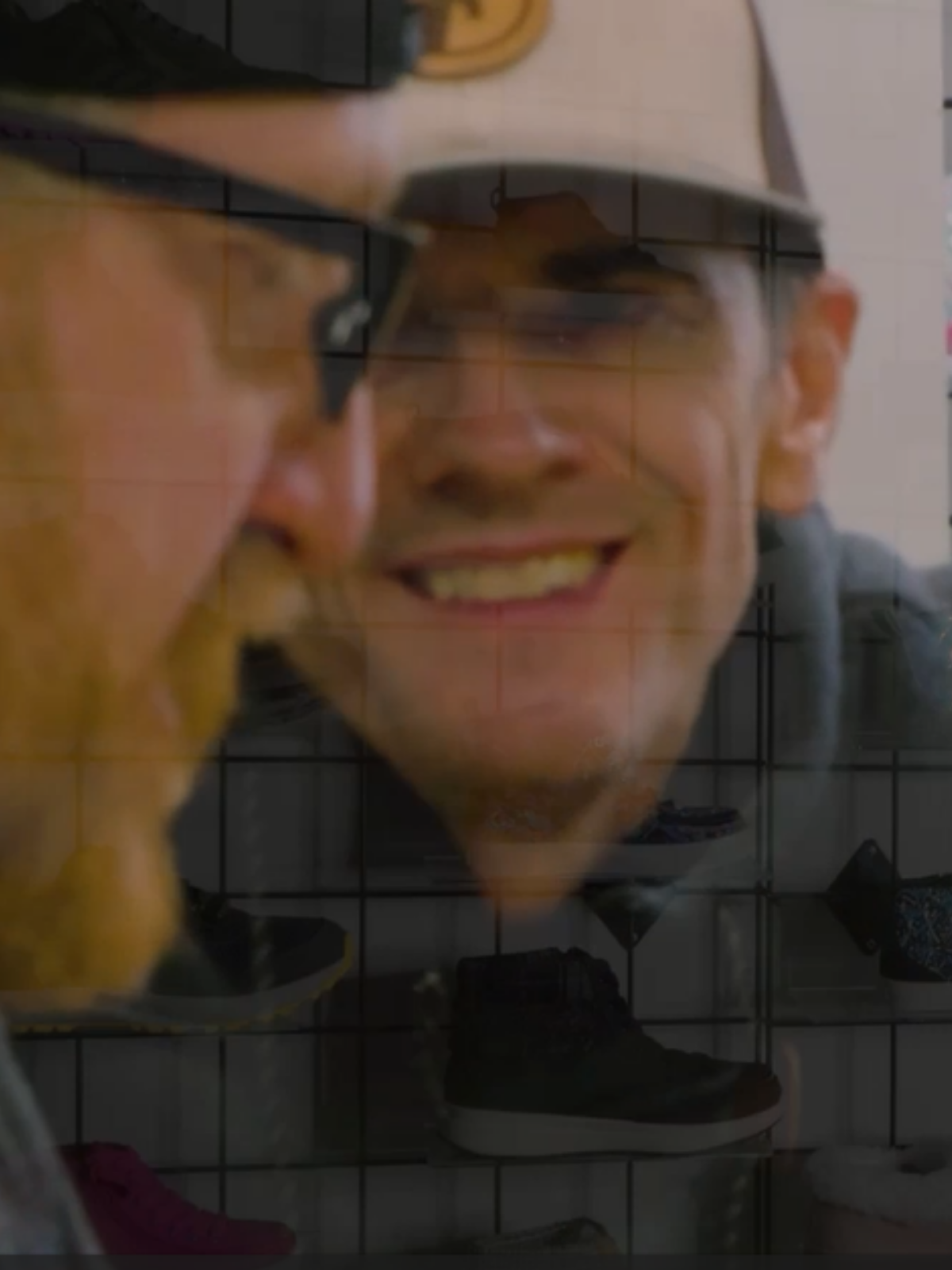Close-up of a person wearing a cap and a person wearing glasses with a blurred background