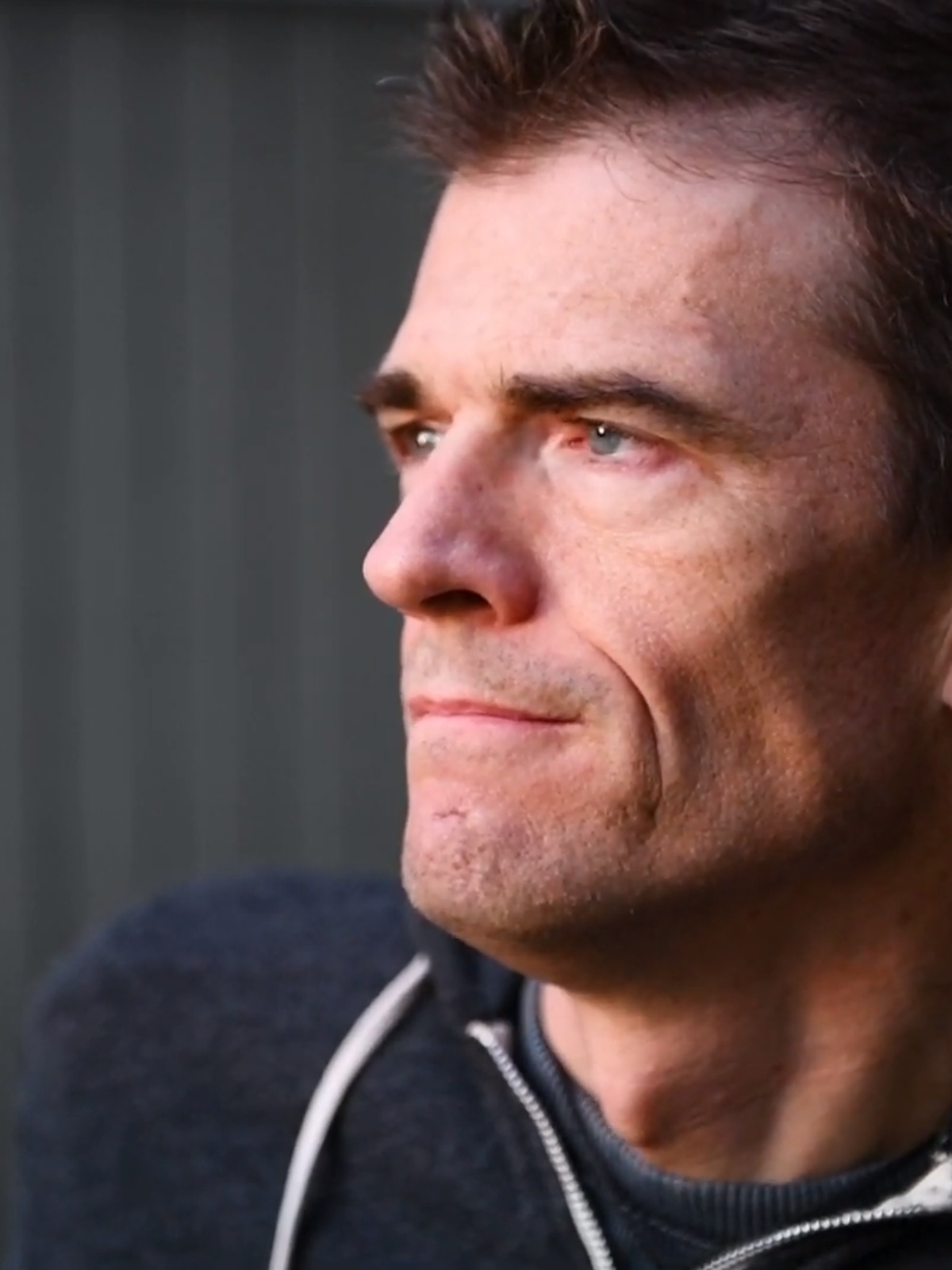 Close-up of a man's face with a neutral expression against a gray background